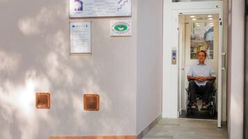 A man in a wheelchair entering a building with a sign reading "Welcome" and a green sign indicating a restaurant.
