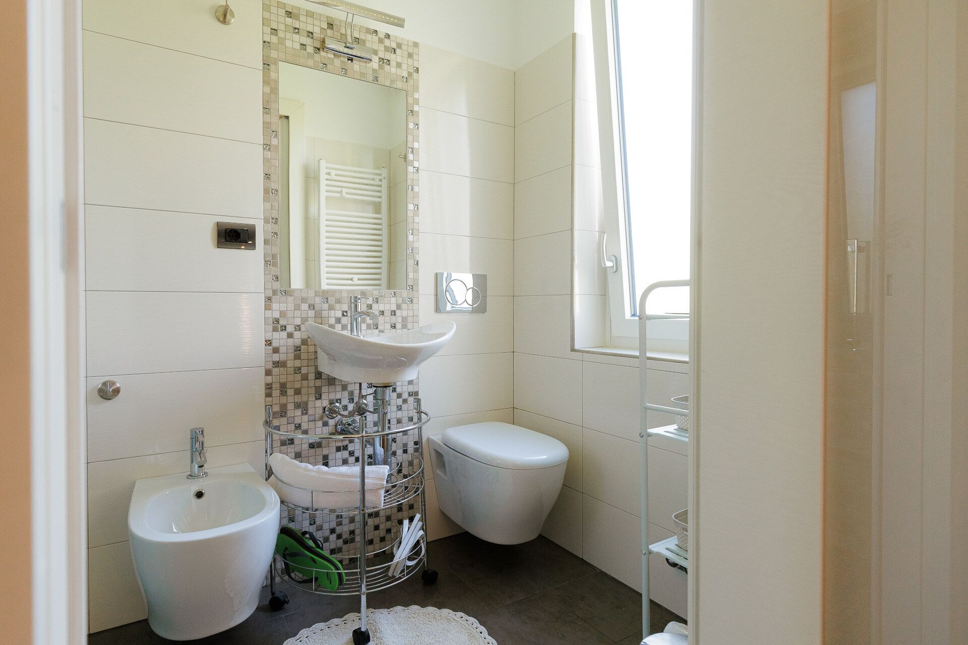 A bathroom with a bidet, a toilet, a sink, and a mirror.