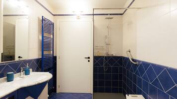 Un baño con una puerta blanca, una zona de ducha con azulejos azules y un lavabo con encimera azul.
