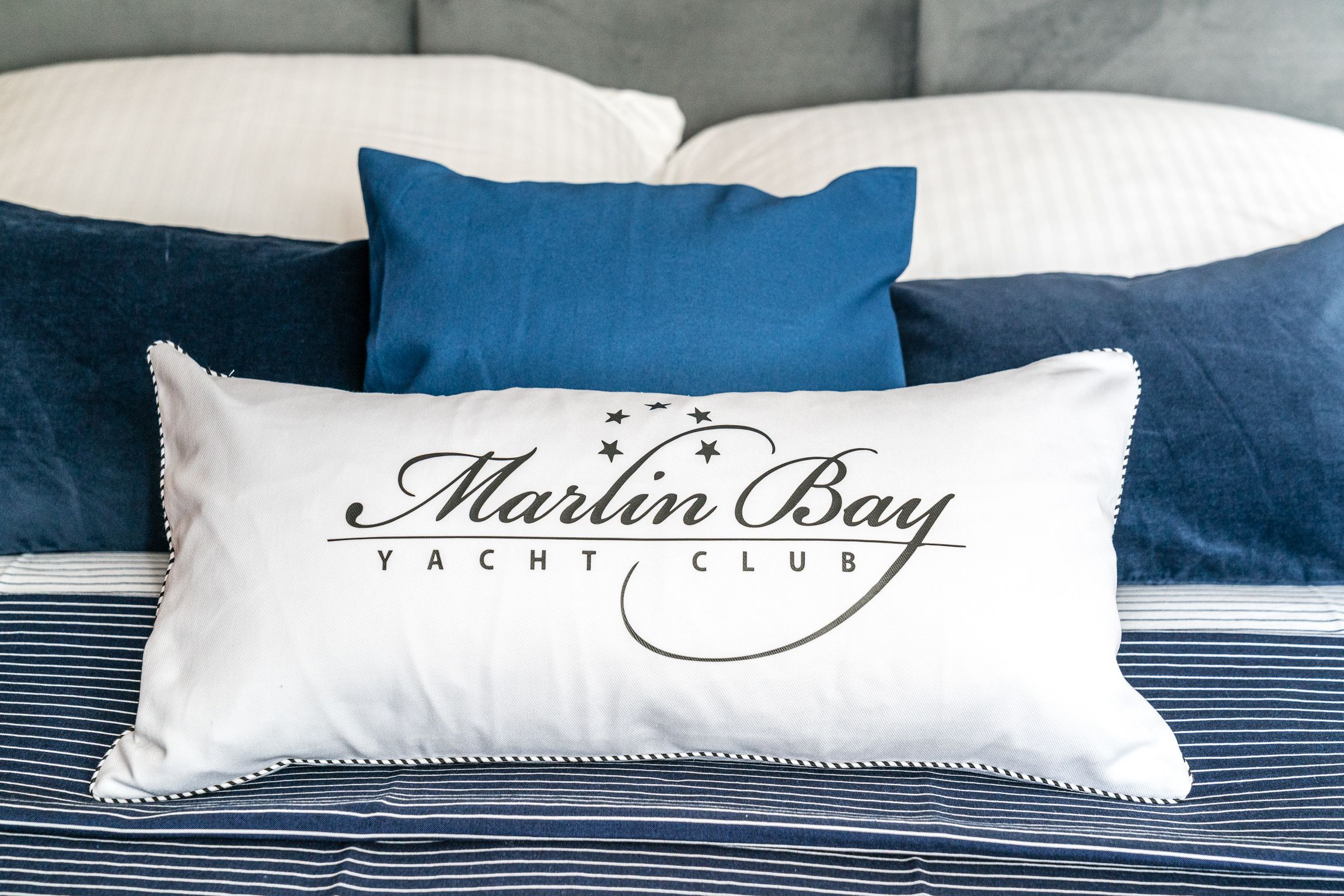 Un letto con un cuscino bianco con la scritta "Marlin Bay Yacht Club".
