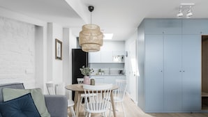 A modern kitchen with white cabinets, a dining table with chairs, and a hanging light fixture. - Sanhaus Apartments - Parkowa (Sopot)