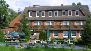 A two-story building with a flat roof and multiple windows. There are outdoor tables and chairs, and a sign that reads "Café". - Landgasthof Allerparadies (Langlingen)