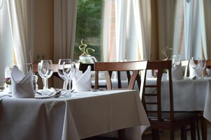 Una mesa de restaurante con mantel blanco, cristalería y cubertería dispuesta con cuidado.