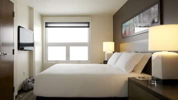 Habitación de hotel con una cama grande, dos lámparas de noche, un televisor de pantalla plana, una ventana y un cuadro en la pared.