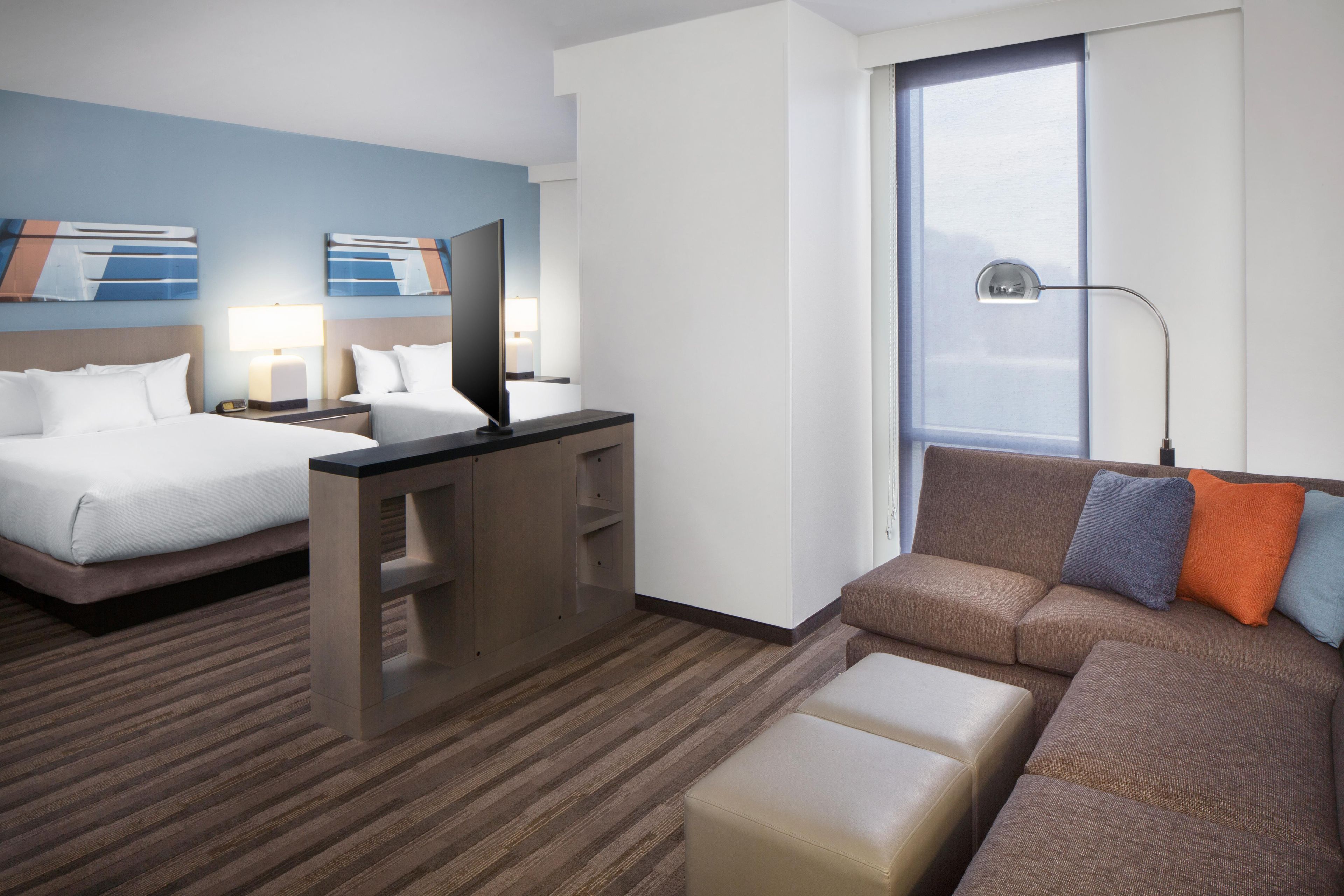 A hotel room with a bed, a sofa, a desk, and a window.