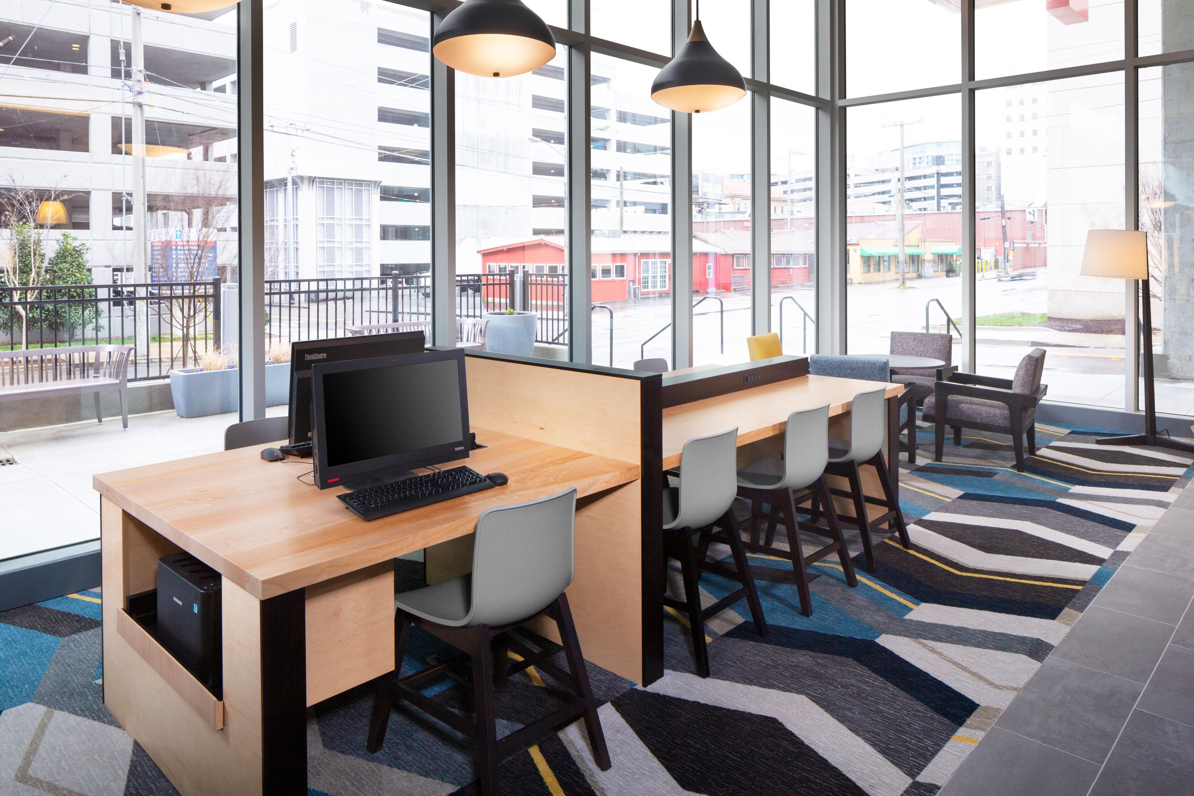 Espaço de escritório moderno com uma grande janela, uma mesa com computador e várias cadeiras.