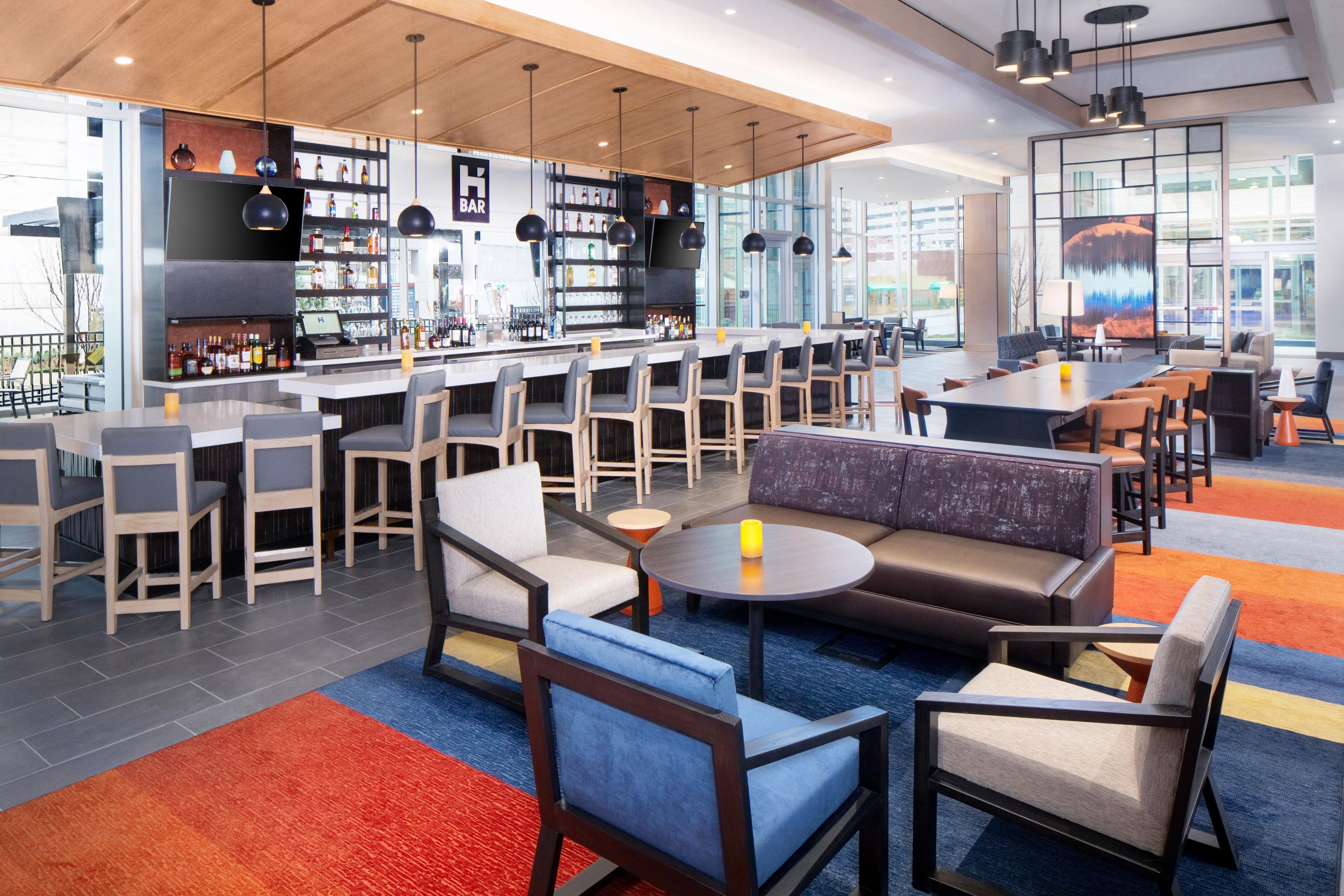 A modern bar area with seating and a bar counter, featuring a mix of bar stools and sofas.