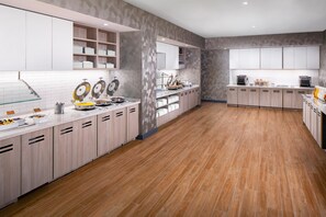 A modern kitchen with white cabinets, a wooden floor, and a breakfast bar with various food items. - Hyatt House Nashville at Vanderbilt (Nashville)