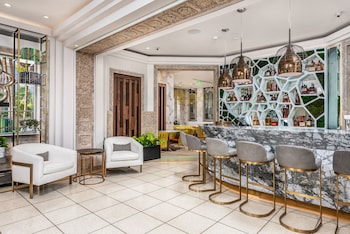 A modern hotel lobby with a wooden staircase, a seating area with a vase of flowers, and a large potted plant. at Lennox Hotel Miami Beach