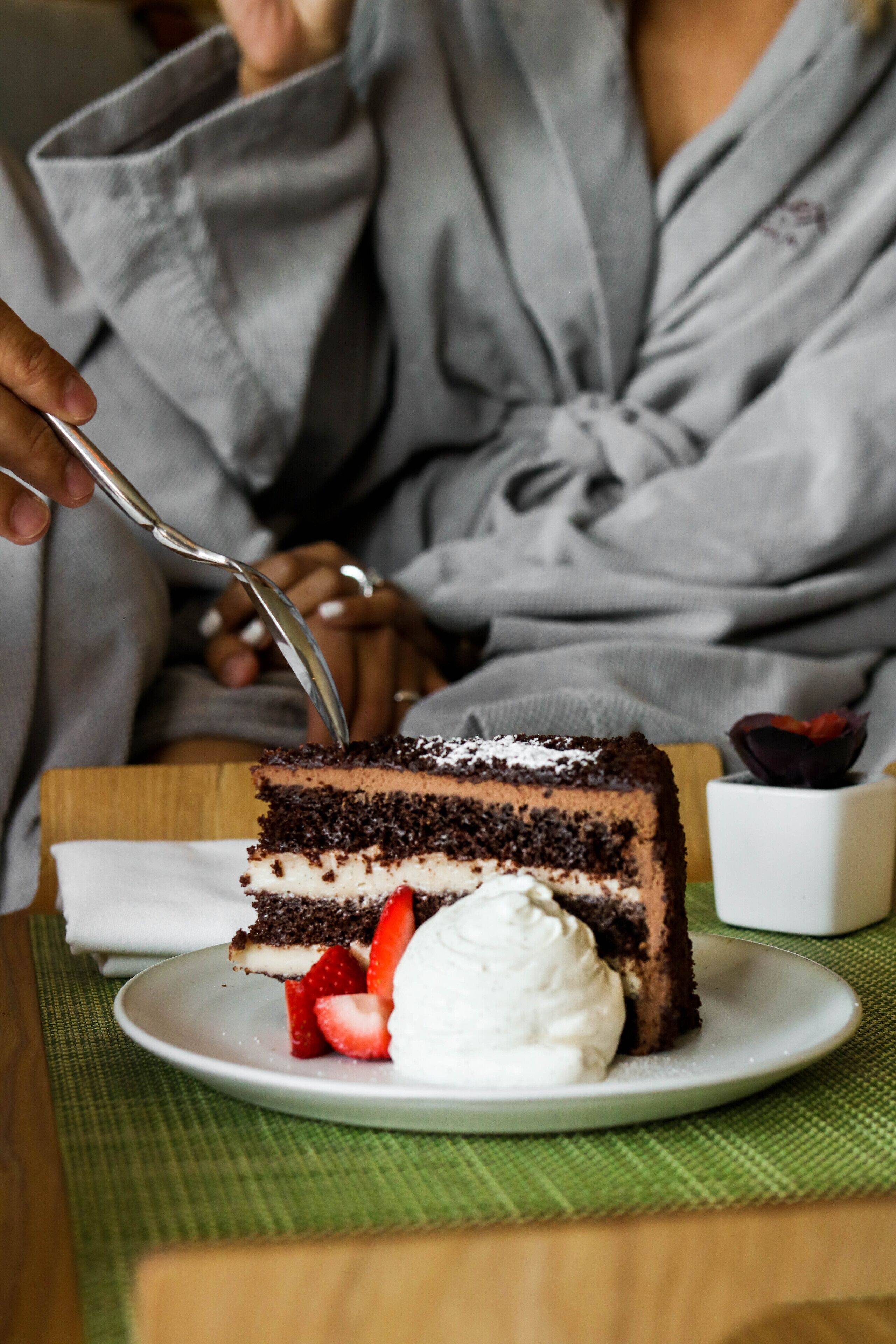 A slice of chocolate cake with strawberries and whipped cream on a plate.