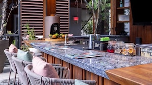 A modern bar area with a marble countertop, wicker chairs, and a variety of bar tools and bottles. - Lennox Hotel Miami Beach (Miami Beach)