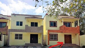 Un edificio residenziale a due piani con tetto piatto, diverse finestre e un ingresso chiuso da cancello.