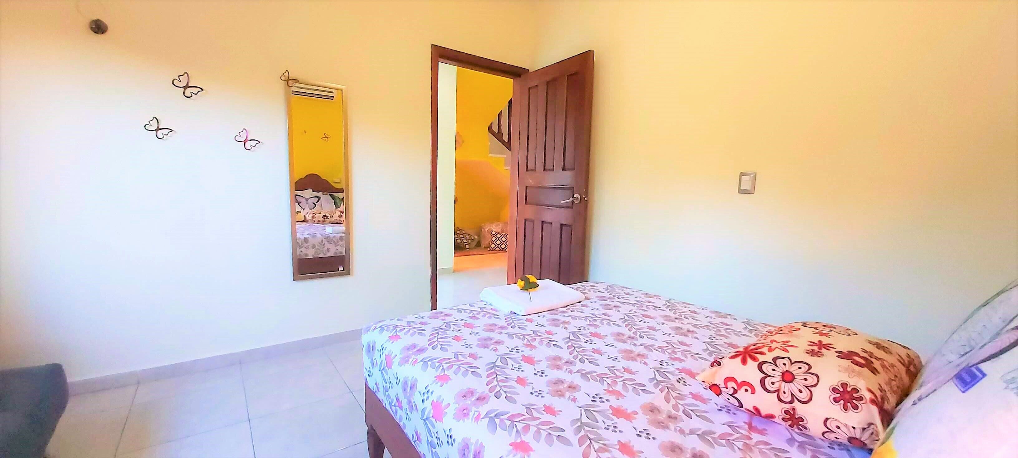 A bedroom with a bed, a door, and a wall with butterfly decorations.