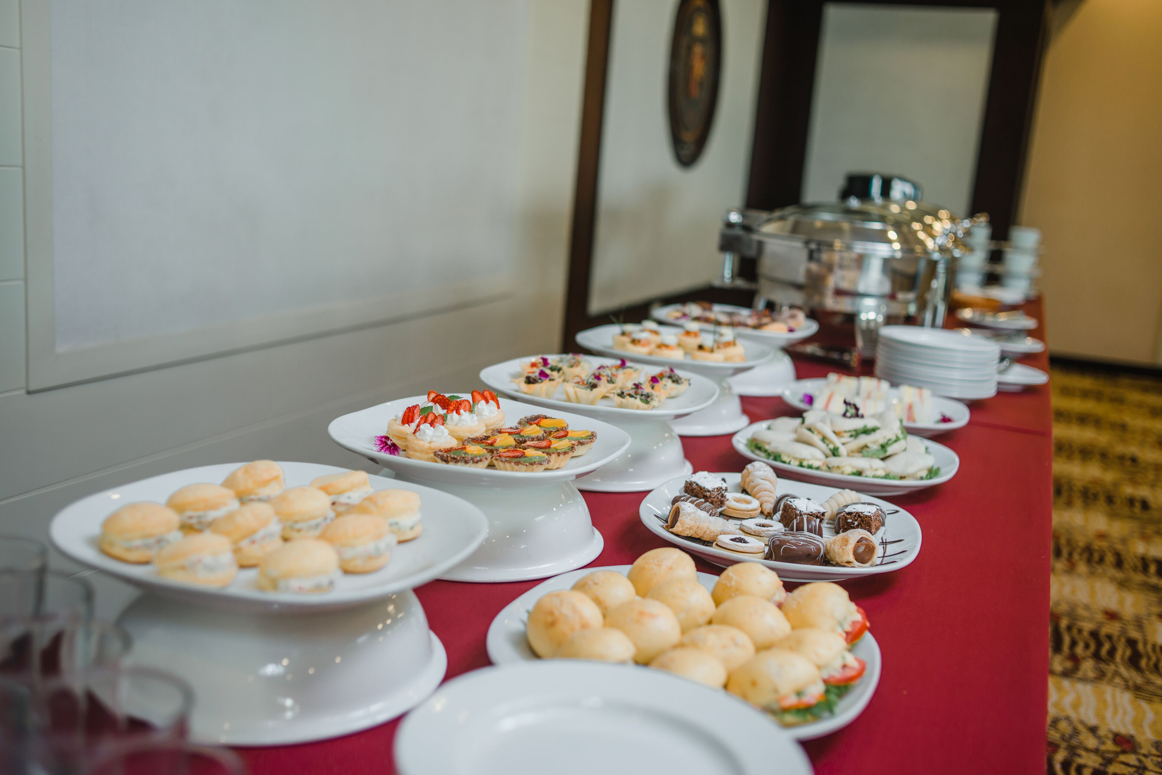 A buffet table with various food items and plates.