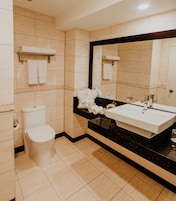 Un baño moderno con inodoro, lavamanos y un espejo grande.