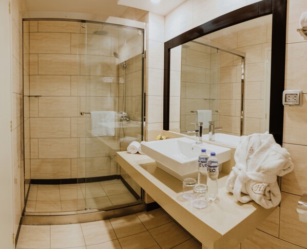 Une salle de bain moderne avec une douche à parois de verre, un grand miroir, un lavabo et un porte-serviettes.