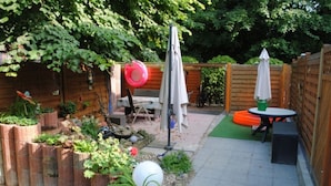 A patio with a table and chairs, surrounded by planters and a wooden fence. - Hotel Garni Nolting (Esens)