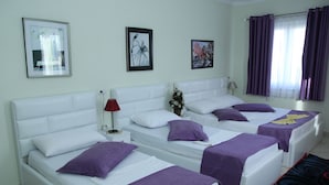 A hotel room with two beds, white headboards, purple bedding, and artwork on the walls. - Hotel Bicaj (Shkodër)