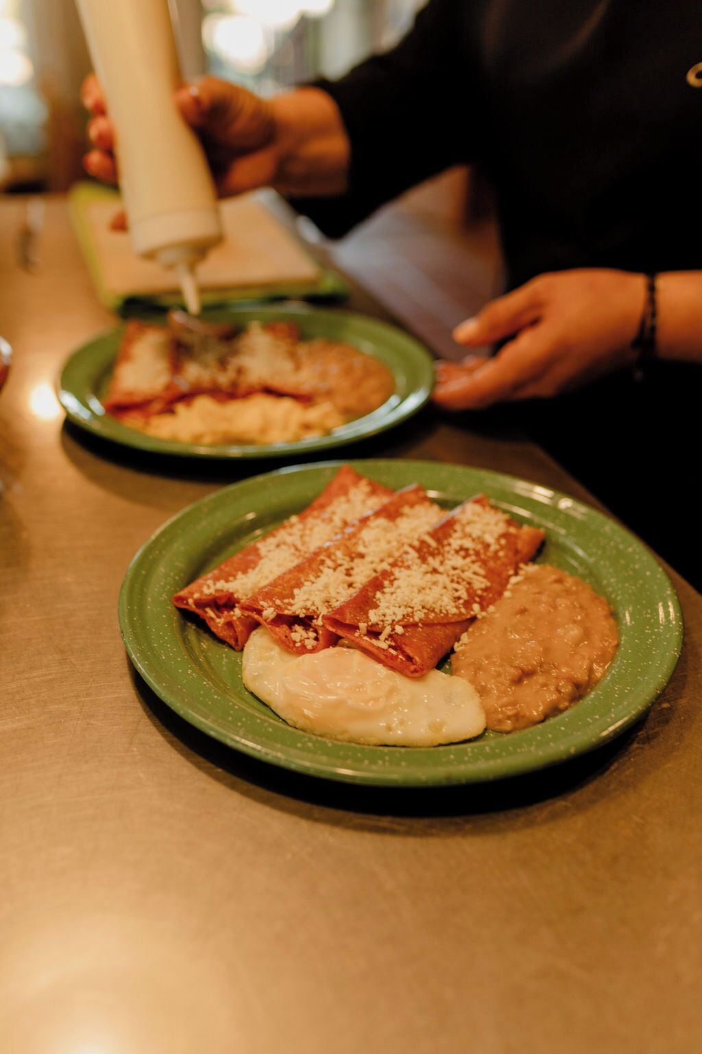 A person pouring sauce onto a plate of food.