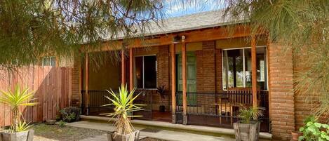 Una casa de madera con porche, paredes de ladrillo y plantas en macetas.