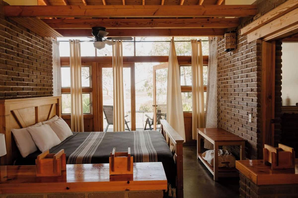 A rustic wooden room with a bed, a table, and a bench.