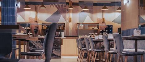 A modern motel interior with a central dining area, multiple tables, and chairs.