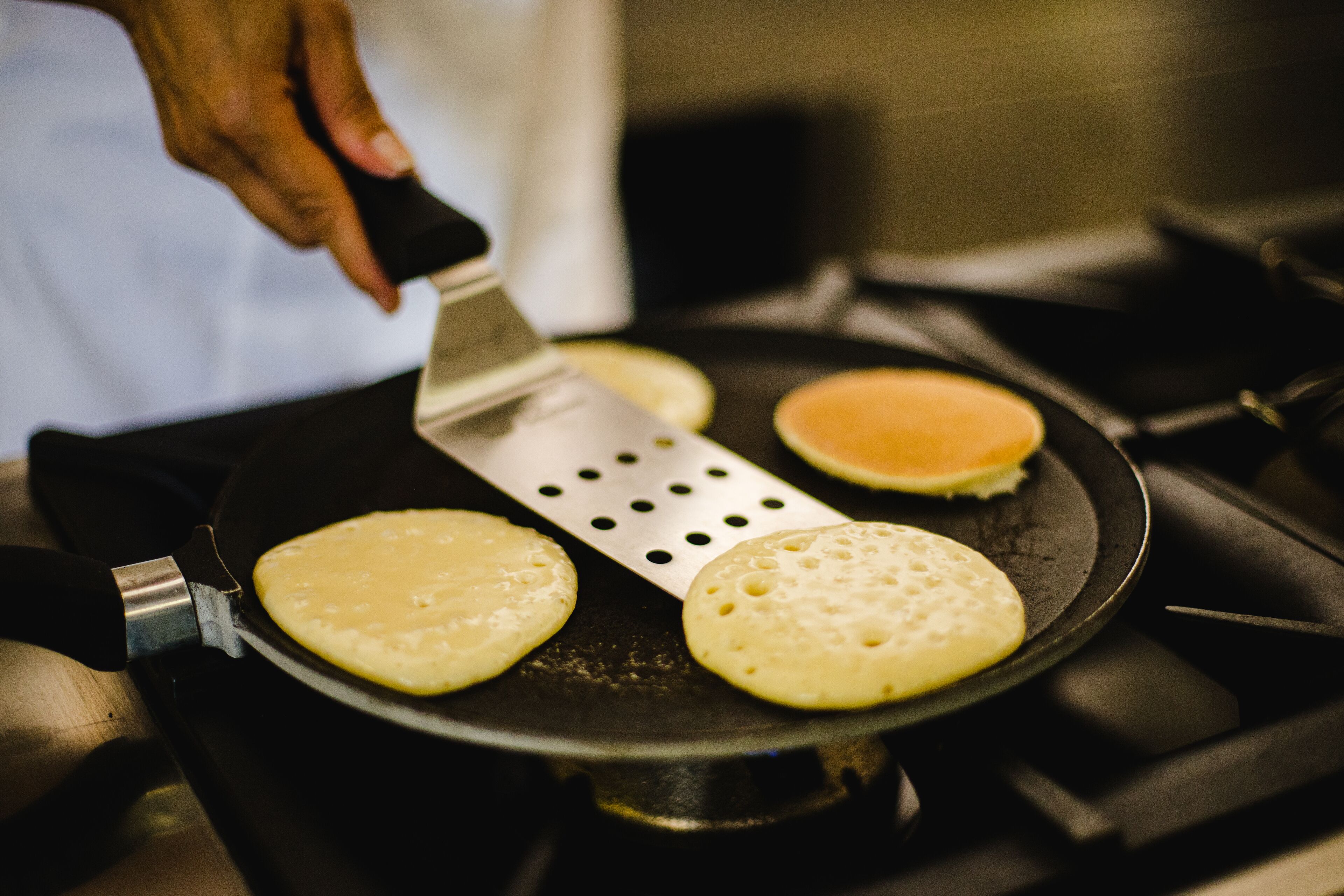 A person cooking pancakes on a stovetop.