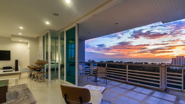 Una sala de estar moderna con un gran ventanal que da a un balcón con vistas a la ciudad.