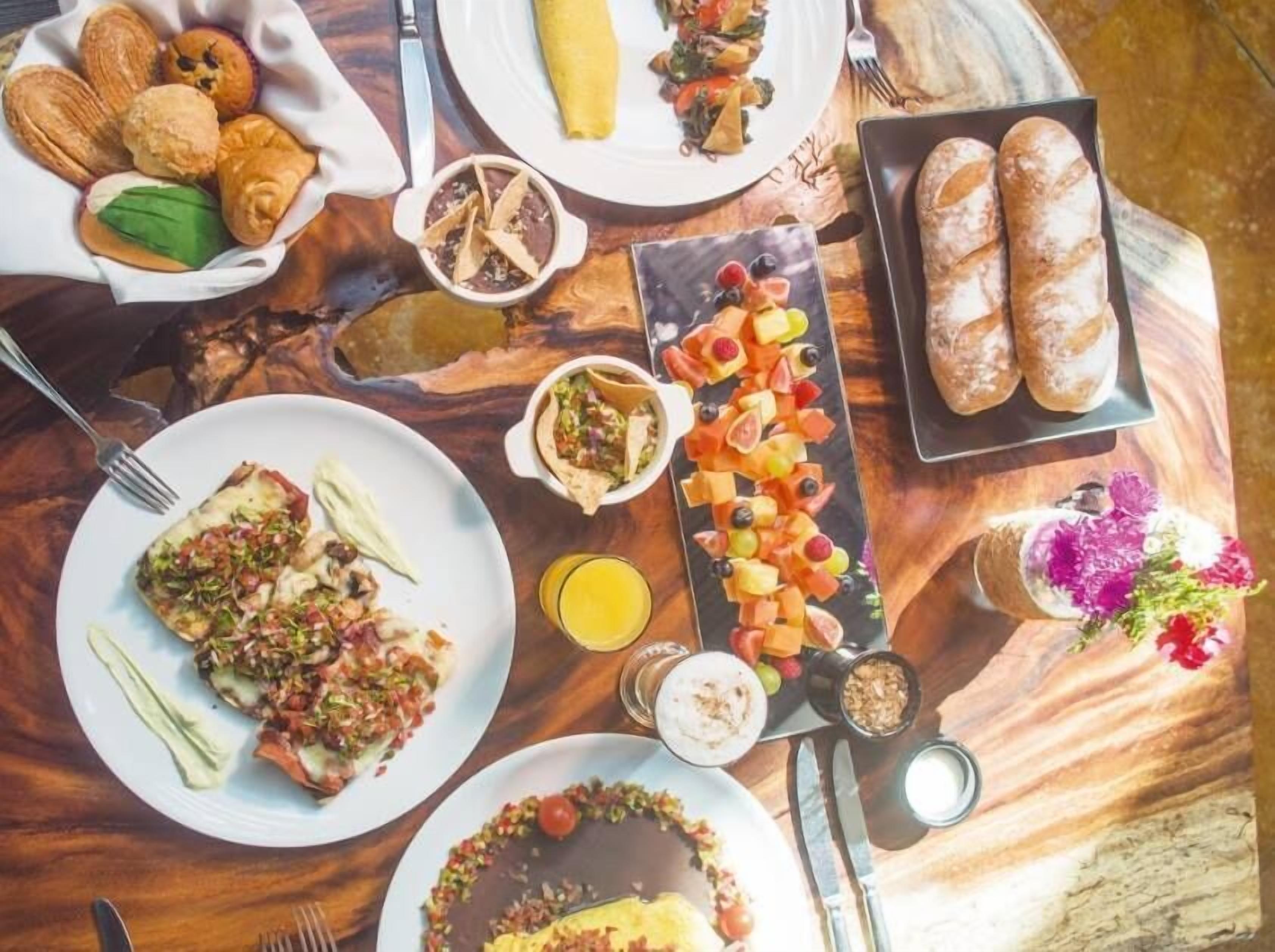 A breakfast buffet with various dishes, including pastries, fruits, and a fruit platter.