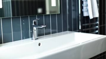 Une salle de bain avec un lavabo blanc, un robinet chromé et un miroir au-dessus.