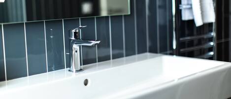 A bathroom with a white sink, chrome faucet, and a mirror above it.