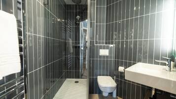 A bathroom with a shower, toilet, and sink.