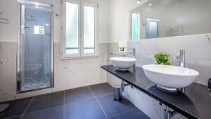 A modern bathroom with a glass-enclosed shower, two sinks, and a large mirror.