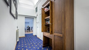 A hallway with a patterned carpet, a wooden cabinet, and a door leading to another room.