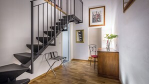 A modern interior with a black spiral staircase, wooden flooring, and a small wooden desk with a chair.