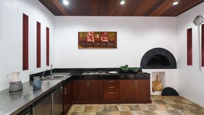 A modern kitchen with a central island, wooden cabinets, a black oven, and a decorative painting on the wall. - Villa Frangipani by Lofty (Rawai)