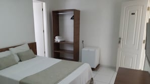 A hotel room with a bed, a wardrobe, a small white cabinet, and a door. - Pousada Tambau Familly (João Pessoa)