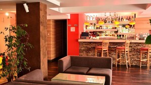 Un espace bar avec un mur en pierre, des tabourets de bar en bois et une variété de bouteilles.