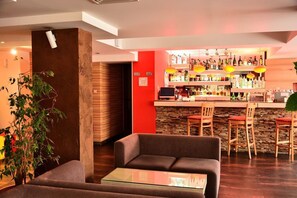 A bar area with a stone wall, wooden bar stools, and a variety of bottles. - Olymp Hotel (Bansko)