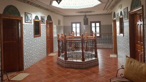 Une pièce avec une table en bois placée au centre, entourée de chaises, des murs à motifs et une lucarne.