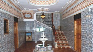 Un couloir aux murs ornés de motifs, un escalier et une fontaine.