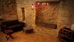 Um quarto aconchegante com parede de pedra, um sofá, uma mesa pequena e um banquinho.