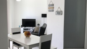 A modern kitchen with white cabinetry, a black countertop, and a dining area with a white table and chairs. - Tu Casa De La Playa Florianópolis Brasil (Florianópolis)