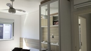 A bedroom with a bed, a wardrobe with a mirror, a ceiling fan, and a window. - Tu Casa De La Playa Florianópolis Brasil (Florianópolis)
