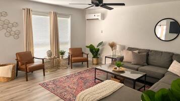 A living room with a sofa, chairs, a coffee table, a floor lamp, and a ceiling fan.