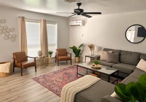 A living room with a sofa, chairs, a coffee table, a floor lamp, and a ceiling fan.