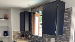 Una cocina moderna con armarios oscuros, un ventanal grande y un salpicadero de azulejos.