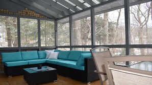 Un espace extérieur aménagé, abrité, avec un canapé d’angle, une petite table et des chaises.