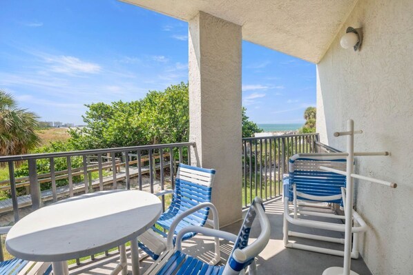 Un balcon avec une table et des chaises, une balustrade et une vue sur l’océan.