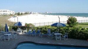 Ein Poolbereich mit Liegestühlen und Sonnenschirmen, Blick auf den Strand und einen klaren Himmel.